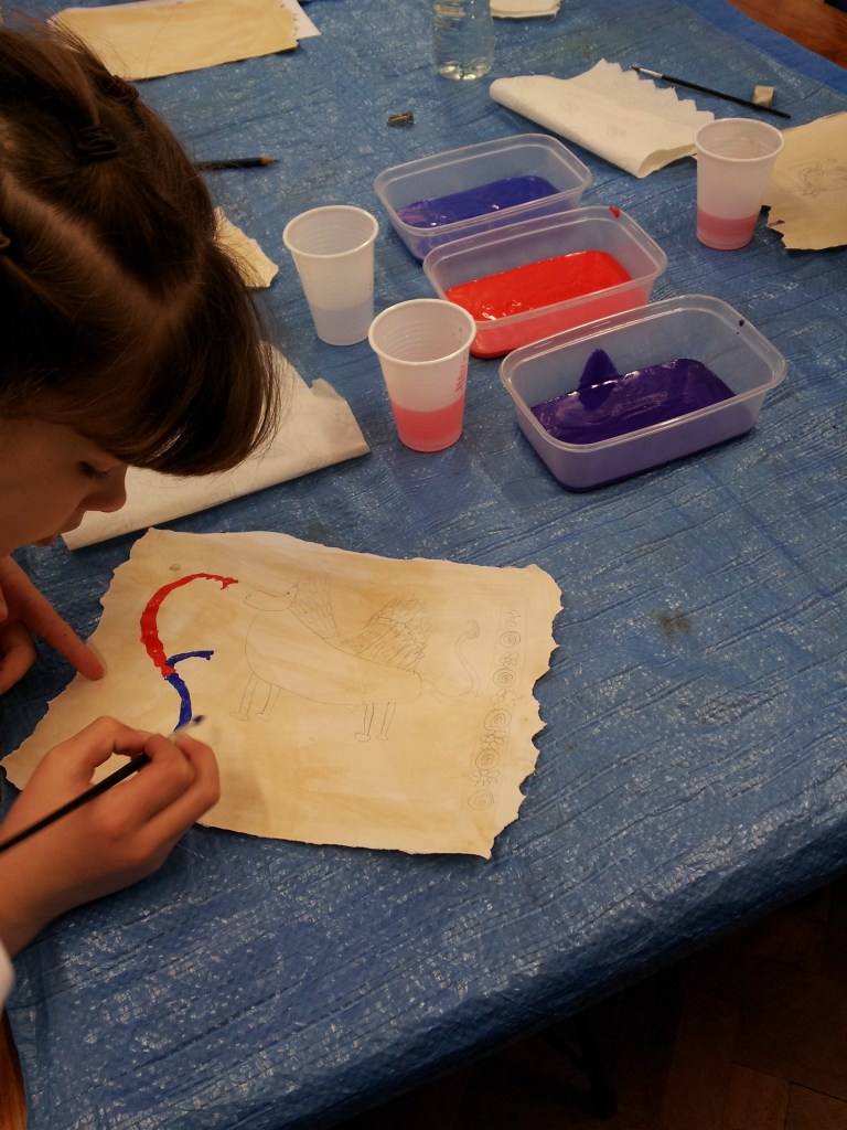 Child paining on paper to create an illuminated medieval manuscripts.