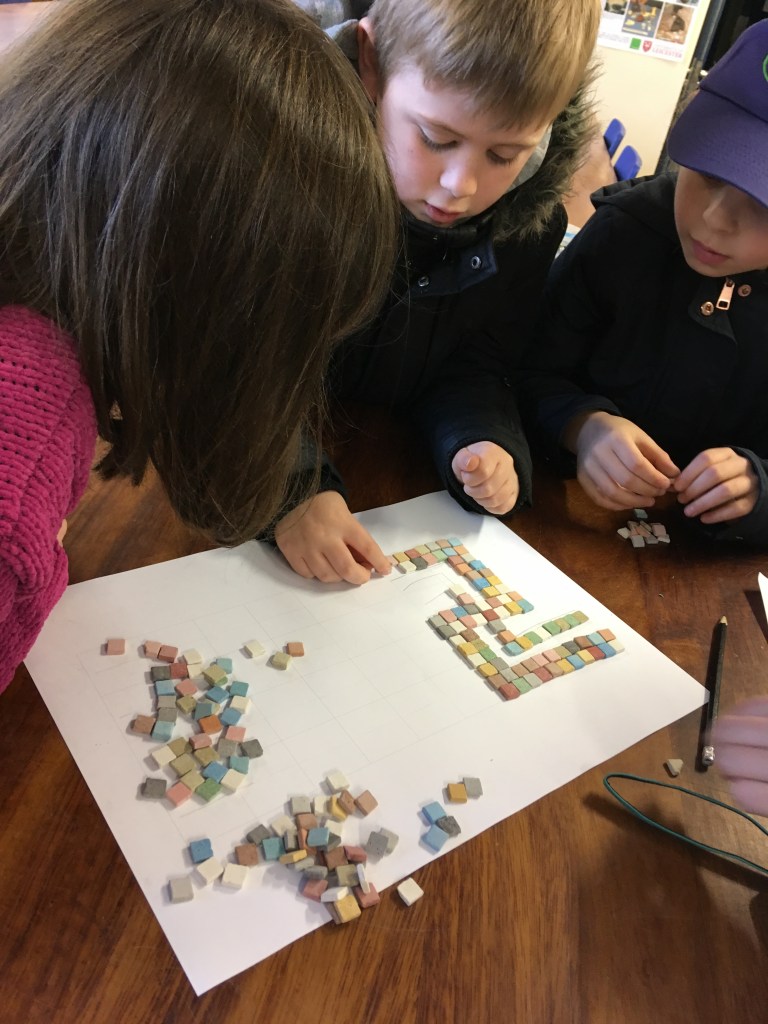 Children designing Roman mosaics with ceramic tiles.